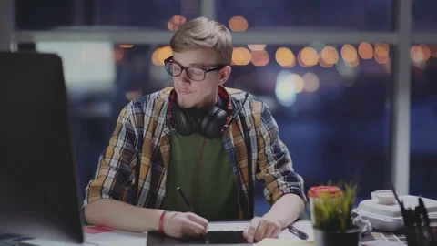 Young designer works in empty office at a later time, feels tired Video stock 87160821