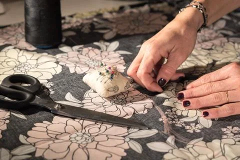 Young designer works in her workshop with colorful and flowery fabrics. Stock Photos