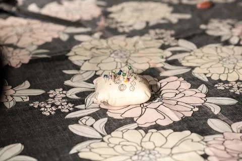 Young designer works in her workshop with colorful and flowery fabrics. Stock Photos
