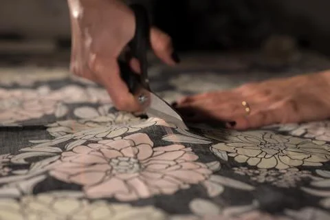 Young designer works in her workshop with colorful and flowery fabrics. Stock Photos
