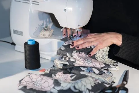 Young designer works in her workshop with colorful and flowery fabrics. Stock Photos
