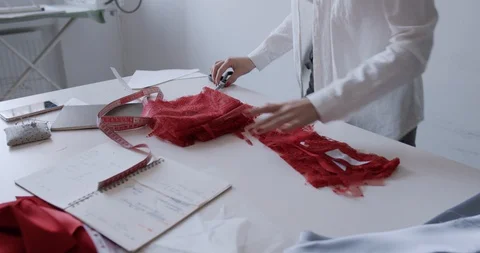 A young designer works in the workshop and cuts textiles with scissors Stock Footage 129858659