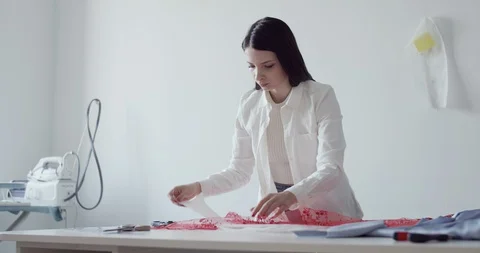 A young designer works in the workshop and cuts textiles with scissors Stock Footage 129864007