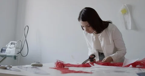 A young designer works in the workshop and cuts textiles with scissors Stock Footage 129866246