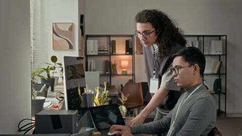 Young Developer Discussing Programming Code with Long-Haired Gen Z Male Coworker Stock Footage 329614540