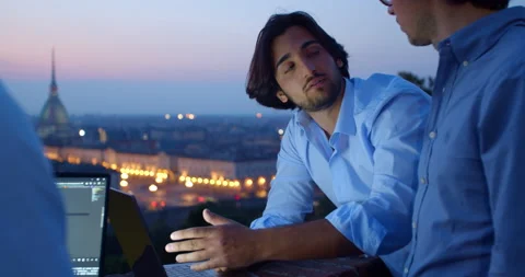 Young developer explains his job. Two businessmen with laptops in the night city Stock Footage 138476709