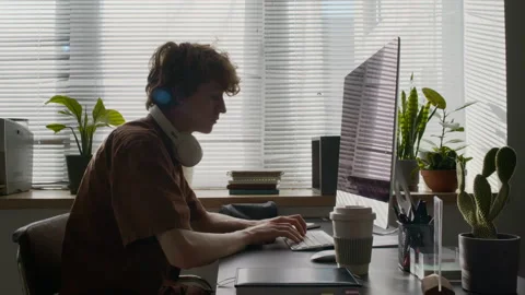 Young Developer with Headphones around Neck Working on Computer in Office 動画素材 299210990