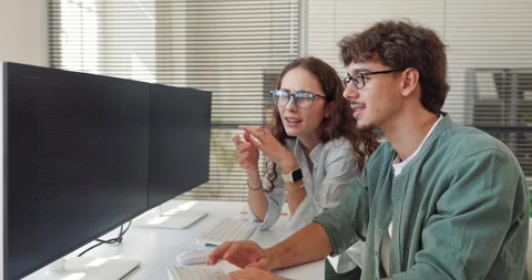 Young Developers Discussing Software Code at Dual Monitor Office Workstation Stock Footage 345680017
