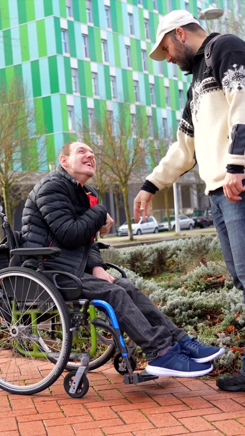 Young disabled man greeting friend in urban setting Stock Footage 301686848
