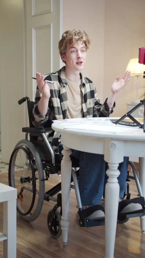 A young disabled man is greeting someone on the Internet and showing charts Stock Footage 163383770