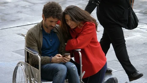Young disabled man looking at smartphone with his friend in the city Stock Footage 121404995