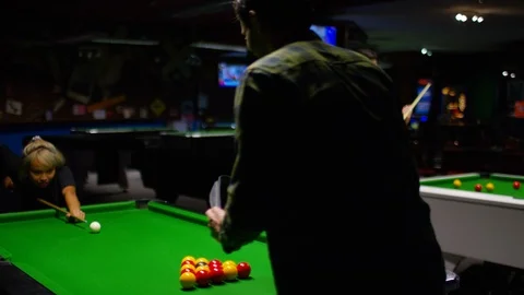 Young diverse couple playing a game of pool in a billiards hall Stock Footage