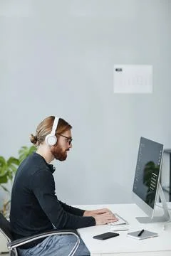 Young diversity programmer in headphones working in front of computer monitor Stock Photos