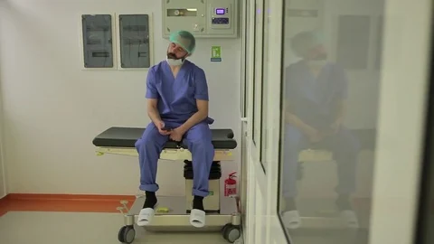 A young doctor with a beard sits on the couch during a break between operations Stock Footage 76705585