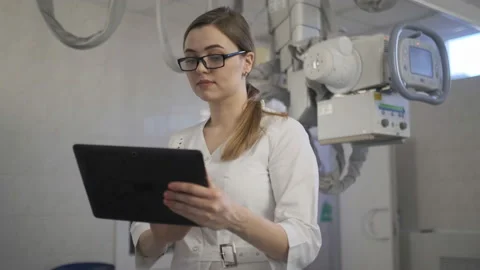 The young doctor checks the diagnosis on the tablet. X-ray machine. Stock Footage 107522853