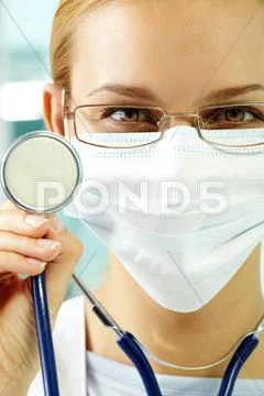 A young doctor in mask and with stethoscope looking at camera and smiling Stock Photos