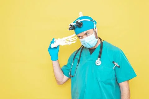Young doctor-surgeon dressed in green on yellow background. Stock Photos