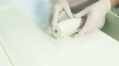 Young doctor unwinds roll with polyurethane tape on table indoors. Stock Footage 76500541