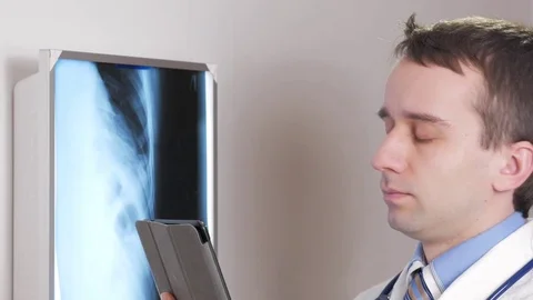 A young doctor uses a tablet computer in the clinic. A man records the results Video stock 73952778