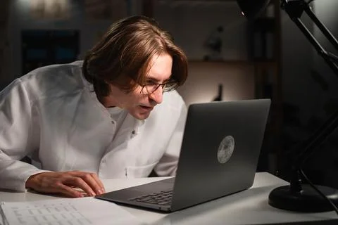 Young doctor using glasses while working on laptop during night shift in hosp Stock Photos