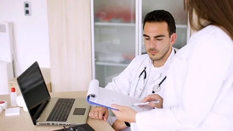 Young Doctors Comparing Data From Patient's Paperboard Stock Footage 87767372