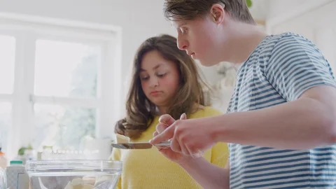 Young Downs Syndrome Couple Adding Butter To Cake Recipe They Are Baking In Stock Footage 114303324