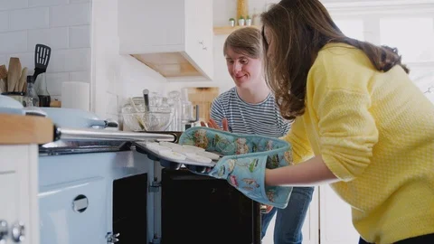 Young Downs Syndrome Couple Putting Homemade Cupcakes Into Oven In Kitchen At Stock Footage 114304595