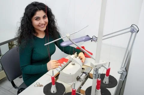 Young dressmaker using professional overlock sewing machine in workshop studio Foto stock