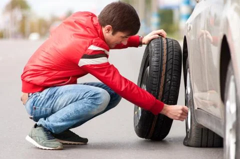 Young driver changing tyre wheel after breakdown Stock Photos