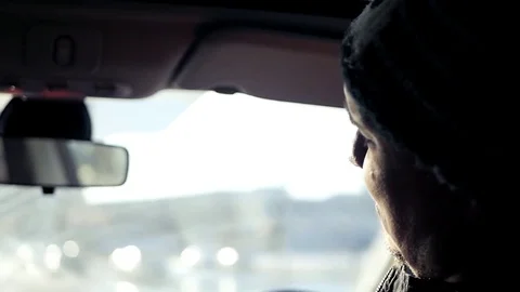 A young driver driving a car rides around the city in the bright sun, talking Stock Footage 73951192