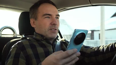 Young driver guy distracted by his phone while in front of the steering wheel Stock Footage 301681698