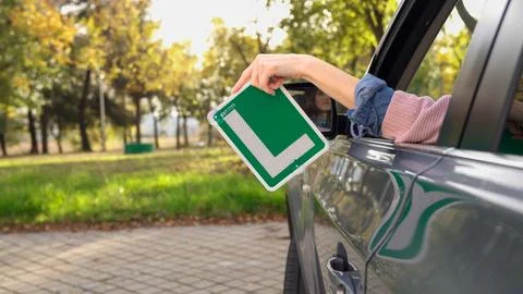 Young driver holding learner plate out of car window Stock Photos