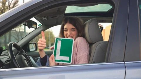 Young driver showing learner permit and giving thumbs up Stock Photos