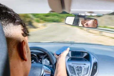 Young driver, using smartphone, on the road in the car. Foto stock