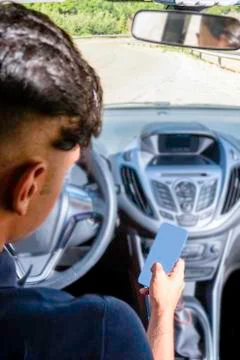 Young driver, using smartphone, on the road in the car. Foto stock
