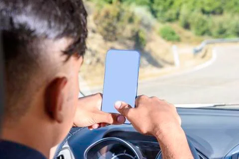 Young driver, using smartphone, on the road in the car. Stock Photos