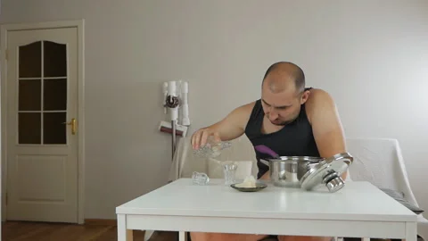 Young drunk guy at home alone at the table drinking alcoholic beverages and Stock Footage 142896892