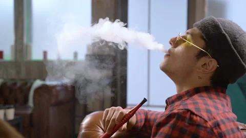 Young eastern man exhaling smoke smoking hookah Stock Footage 106337652