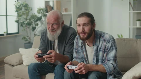 Young, elderly man happily spending time playing a computer game with joysticks Stock Footage 263404975