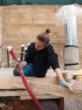 Young electrician lying on the ground assembling the and holding a red tube Stock Photos