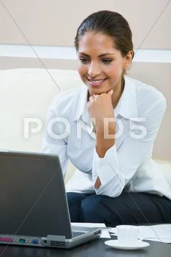 Young elegant business woman looks at her laptop and thinks about a new plans Stock Photos