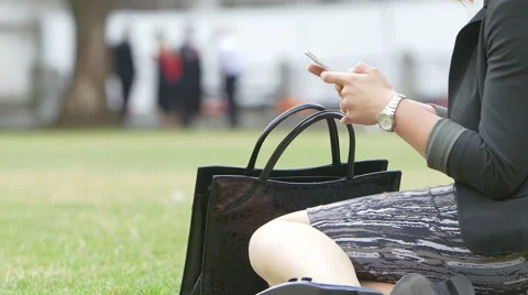Young elegant woman using cell phone sitting on the grass Stock Footage 56959702
