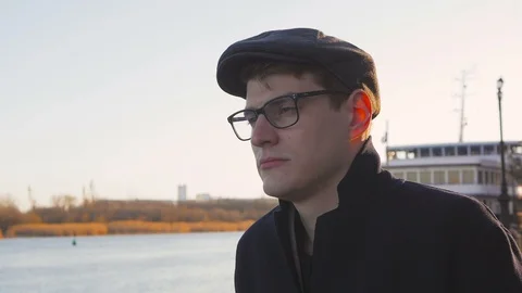 A young, elegantly dressed man stands by the river and looks thoughtfully into Stock Footage 105045837