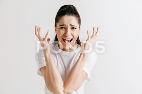 The young emotional angry woman screaming on gray studio background Stock Photos