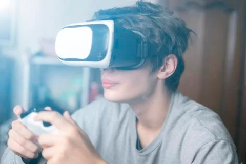 Young emotional boy using virtual reality vr headset at home and play games Foto stock