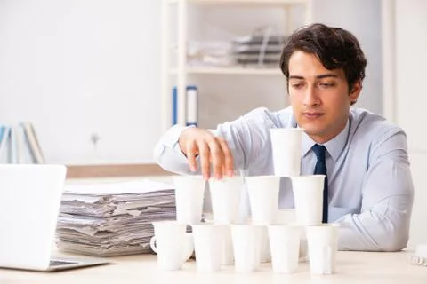Young employee building pyramid from plastic cups Stock Photos