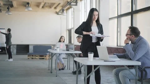 Young employee communicates with colleagues, and gives them tasks. Coworking Stock Footage 108939730