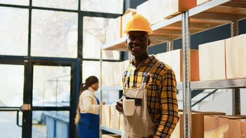 Young employee posing next to boxes on shelves Stockfoto's