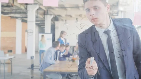 A young employee in a suit prepares a presentation and draws graphics on a glass Stock Footage 109567401