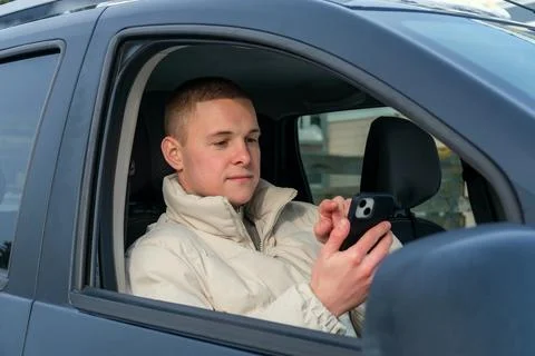Young employee using smartphone during winter commute, checking messages in.. Stock Photos